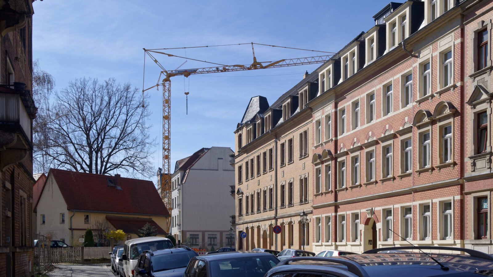 Baustelle eines neuen Mehrfamilienhauses mit Baukran in einer deutschen Stadt bei Tageslicht