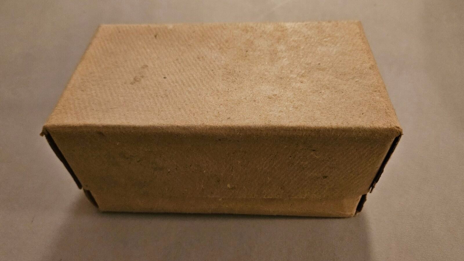 Schlichter brauner Versandkarton aus Pappe auf einem grauen Boden