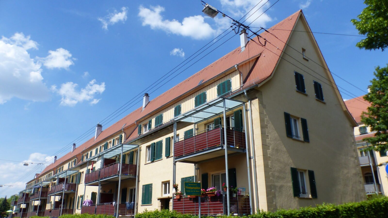 Mehrfamilienhaus mit Balkonen in einer Wohnsiedlung in Stuttgart unter blauem Himmel
