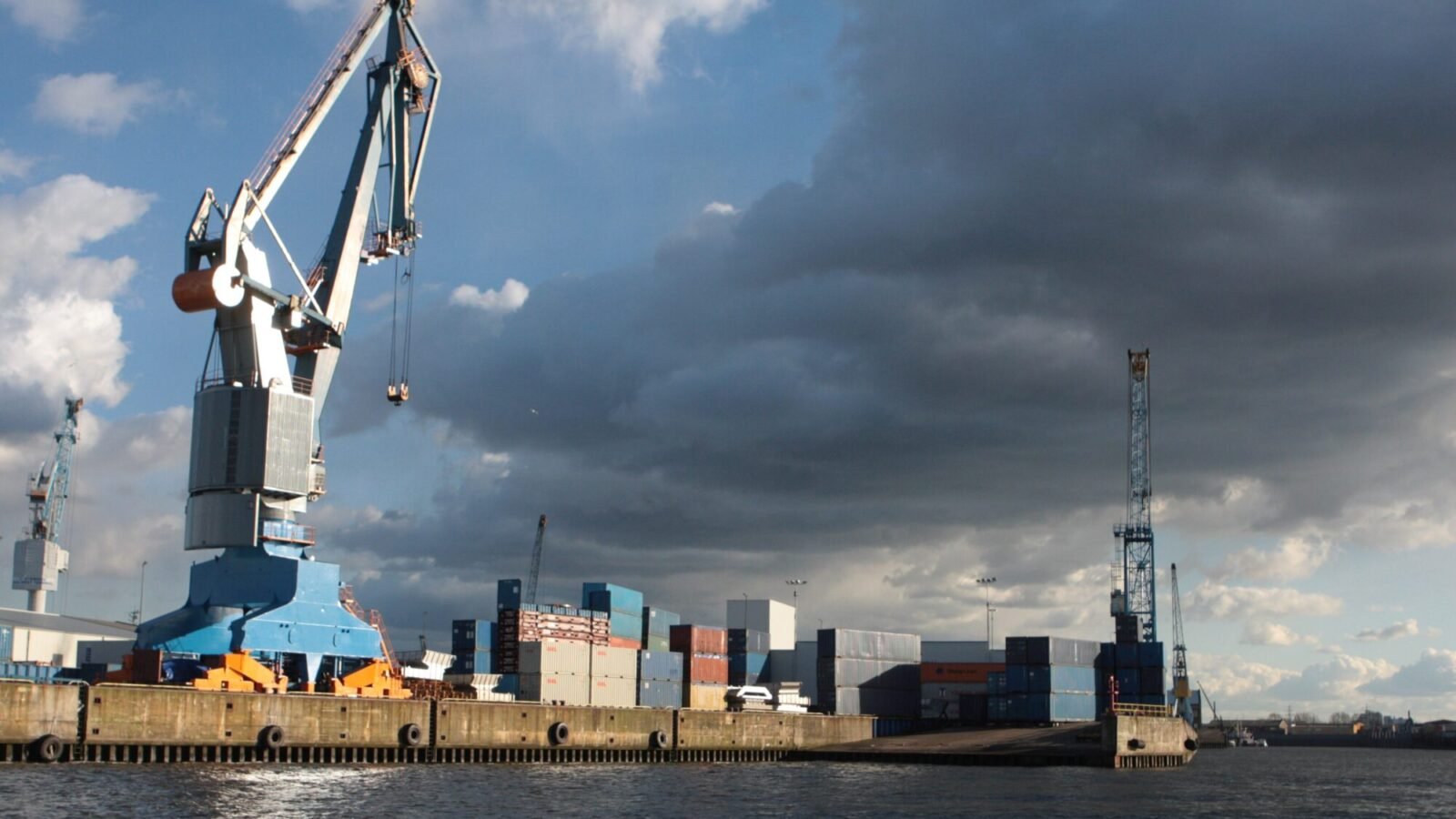 Hafenkran und Container am Kai des Hamburger Hafens unter bewölktem Himmel