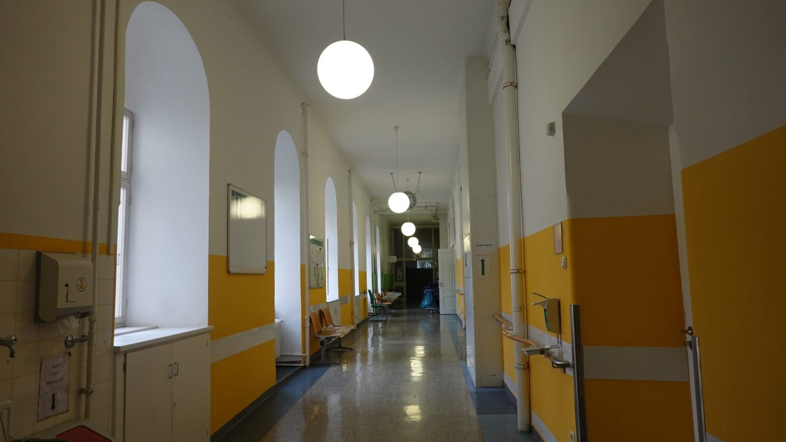 Leerer langer Krankenhausflur mit gelben Wänden und Deckenleuchten in einer Münchner Klinik