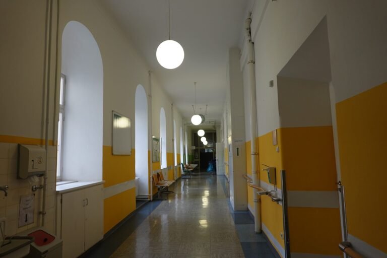 Leerer langer Krankenhausflur mit gelben Wänden und Deckenleuchten in einer Münchner Klinik