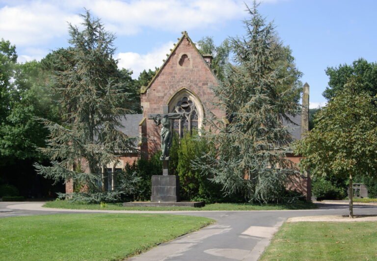Backsteinkapelle auf dem Trierer Hauptfriedhof zwischen Bäumen und Rasenflächen